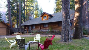 A log cabin with a porch, surrounded by tall trees. - Enjoy Our Beautiful Log Home  (McCloud)
