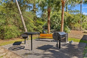 Ein Parkbereich mit Grill, Bank und Picknicktisch.