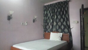 Un dormitorio con cama, una ventana con cortinas estampadas y lámparas fijadas a la pared.