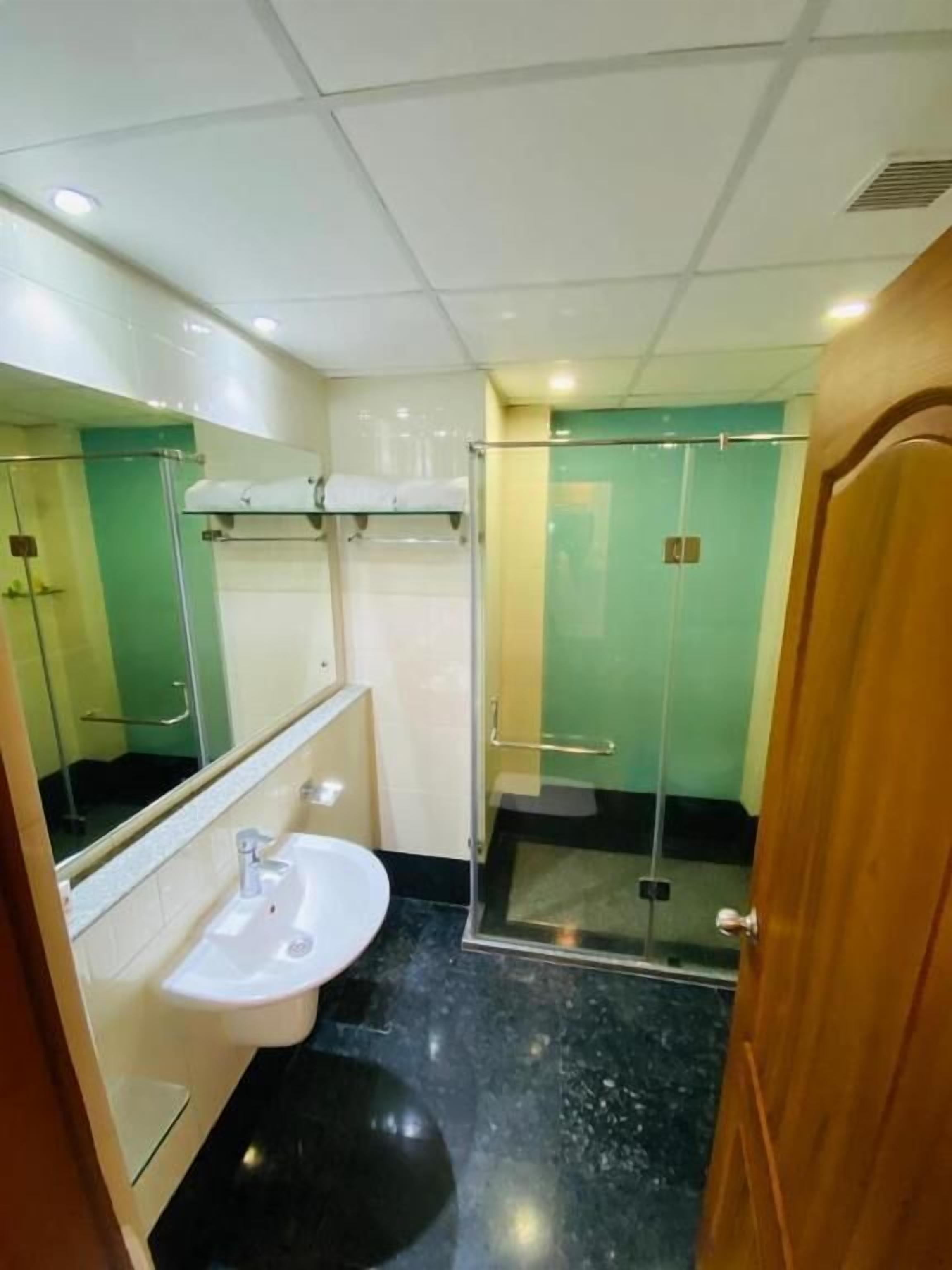 Casa de banho com lavatório, espelho e cabine de duche em vidro.