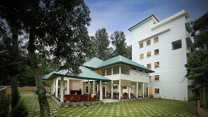 A hotel with a covered outdoor seating area, a courtyard with a patterned floor, and a multi-story building in the background. - PepperVine (Peermade)
