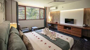 A hotel room with a bed, a desk, a TV, and a ceiling fan. - PepperVine (Peermade)