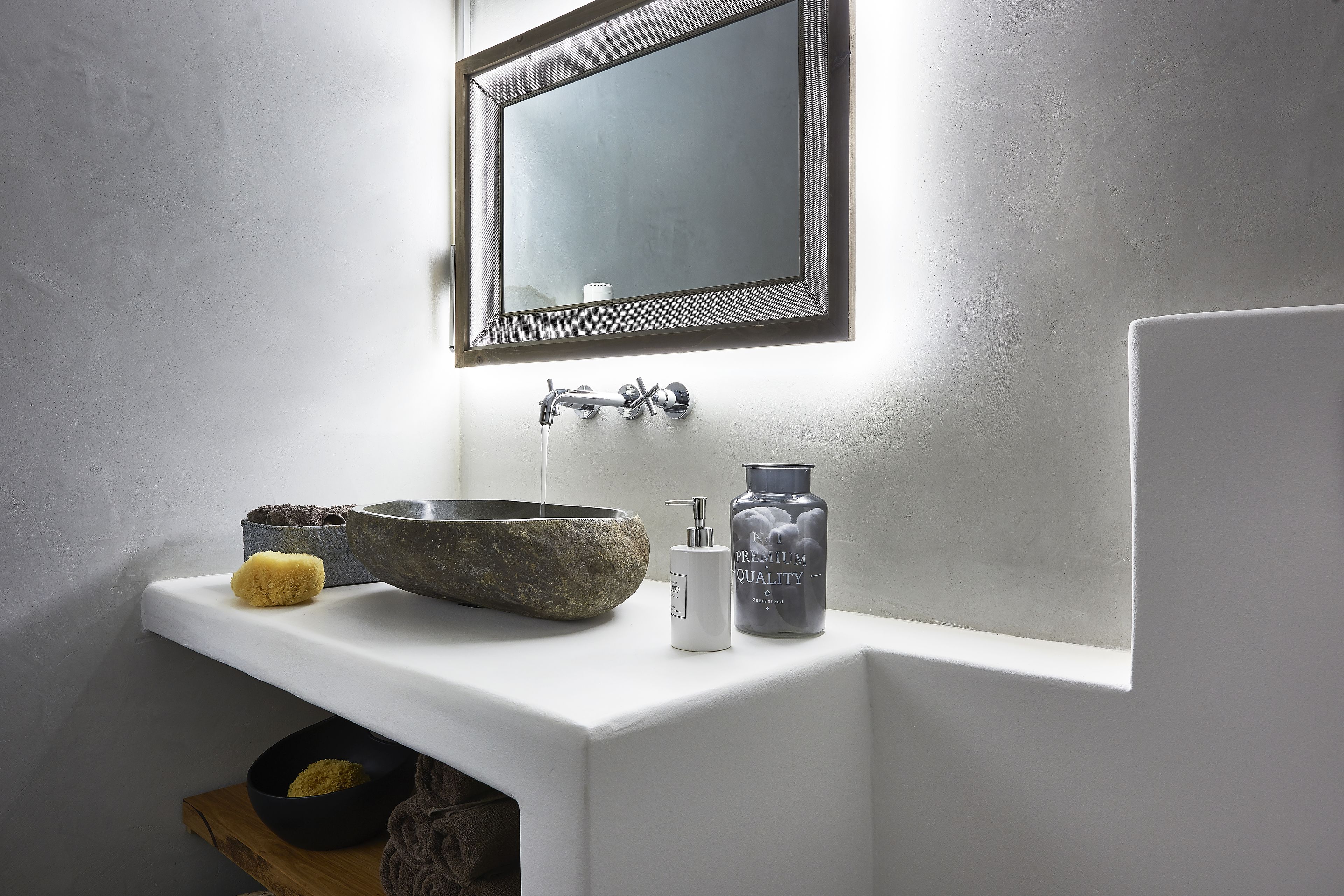 A bathroom with a white sink, stone basin, and a mirror above it.
