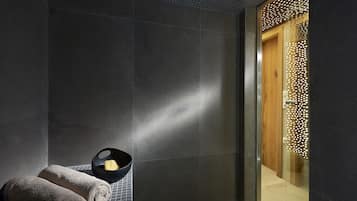 Experience a tranquil bathroom retreat with a sleek dark tiled wall, elegant door, and thoughtful amenities.