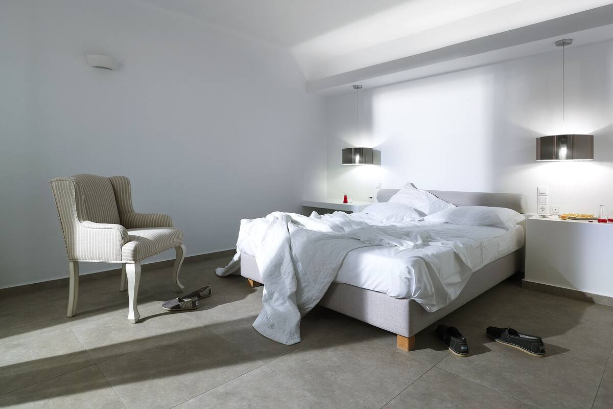 Ein modernes Schlafzimmer mit einem Bett, einem Sessel und einem Nachttisch.