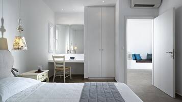 A bedroom with a bed, bedside table, chair, desk, wardrobe, and a view of the balcony.