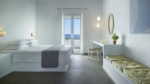 A modern bedroom with a bed, a desk, and a view of the sea. - Santa Maria Luxury Suites & Spa (Milos)
