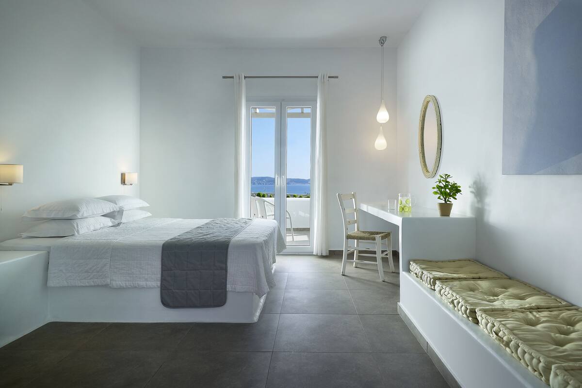 Ein modernes Schlafzimmer mit Bett, Schreibtisch und Blick aufs Meer.