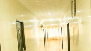 Un long couloir bien éclairé, doté d’un sol en marbre et de portes des deux côtés.