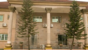 Un bâtiment doté de grandes colonnes, d’un toit recouvert de tuiles et de plantes en pot.