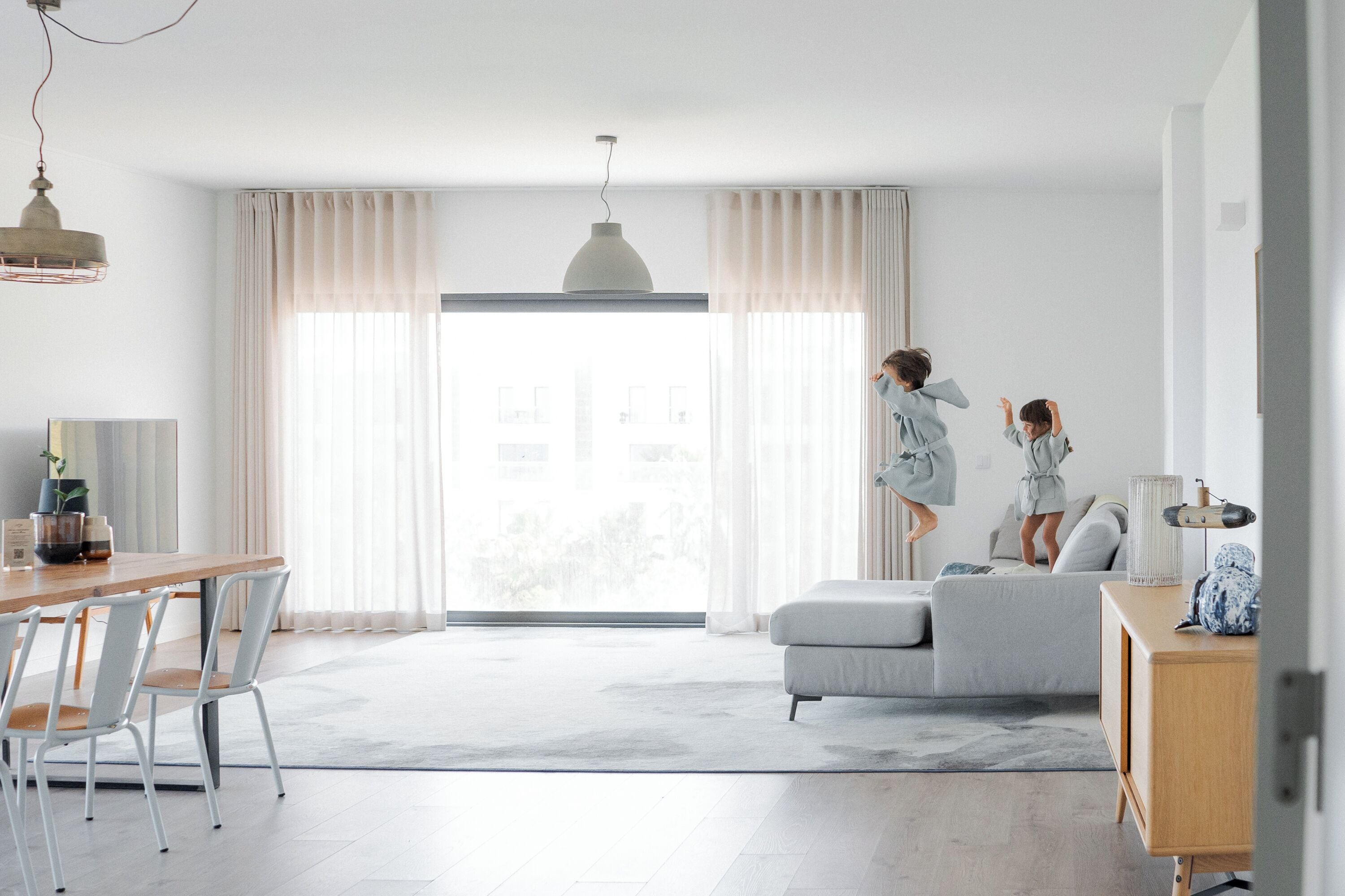 Ein modernes Wohnzimmer mit Essbereich, einer Couch und einem Holzschrank.