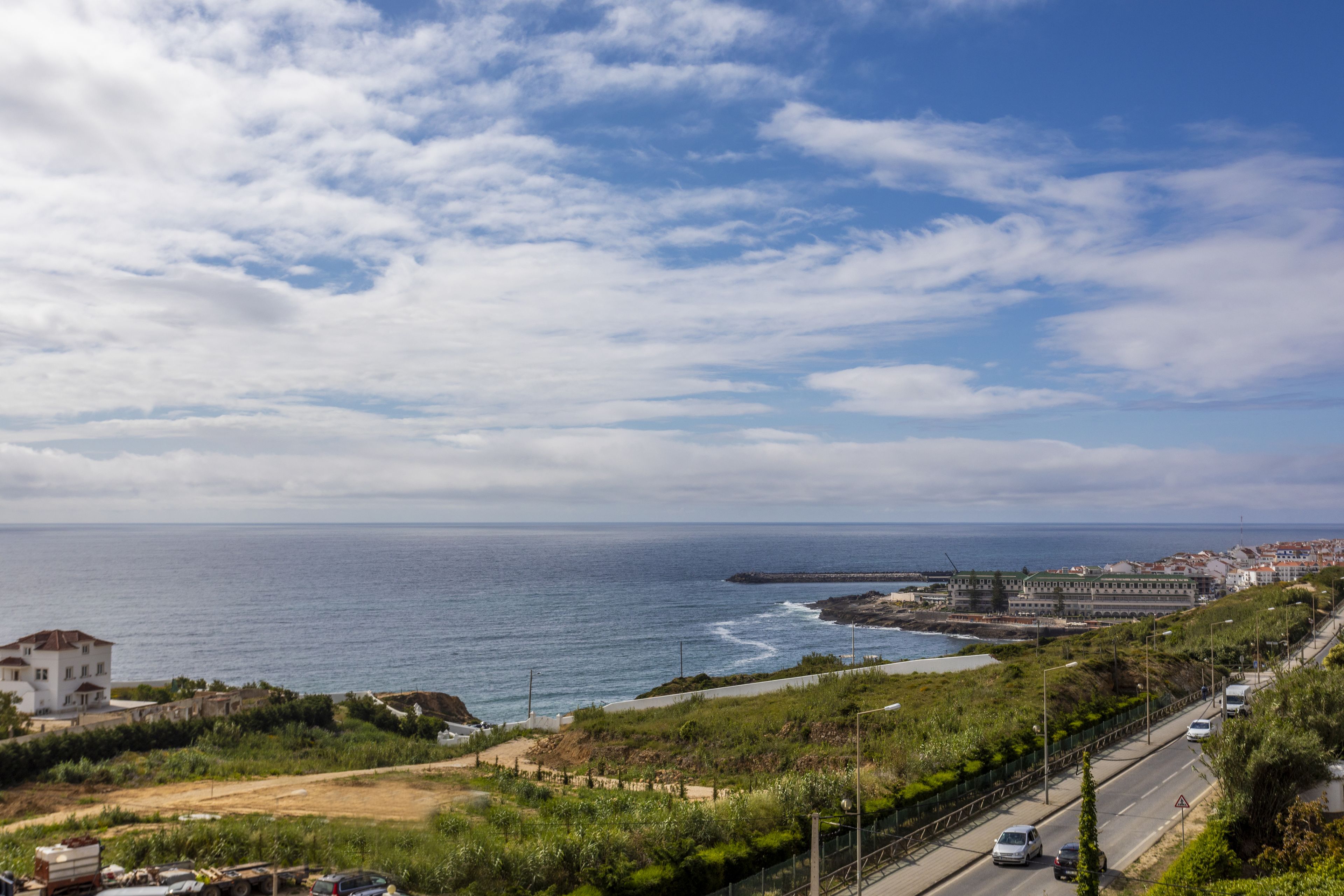 Una carretera costera con vista al mar y un paisaje urbano distante.