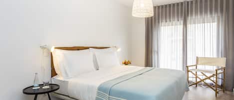 A neatly arranged hotel room with a bed, bedside table, and a chair.