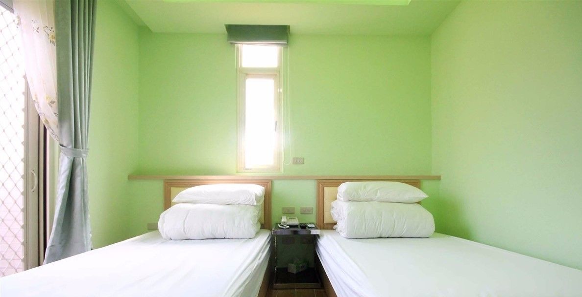 Una habitación con dos camas individuales, una mesita y una ventana.