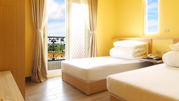 Une chambre d’hôtel avec deux lits, un balcon et une vue sur la verdure.