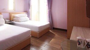 Une chambre d’hôtel avec deux lits, une petite table avec une lampe et une fenêtre avec des rideaux.