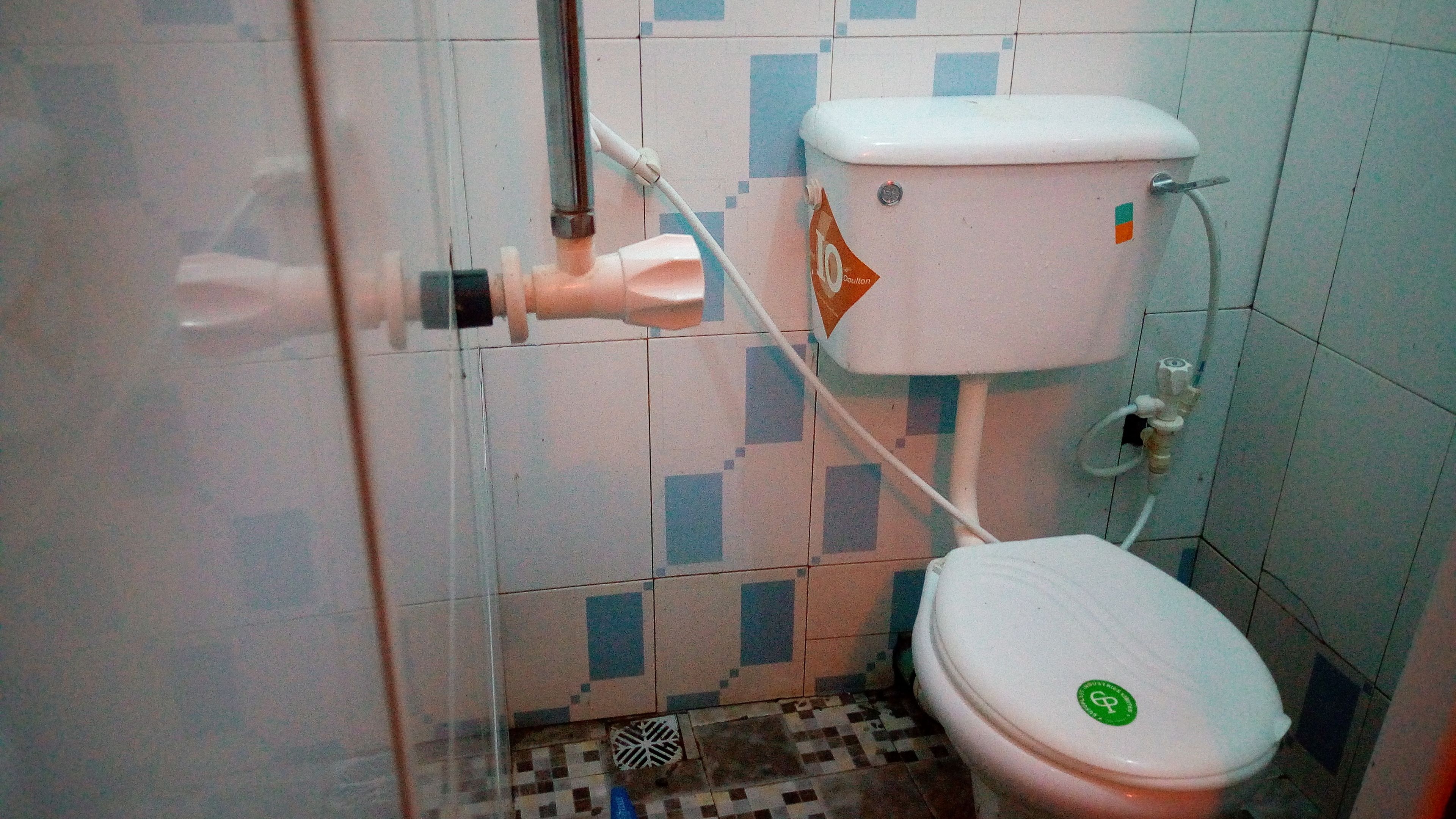 A small bathroom with a toilet, a hand dryer, and a tiled floor.