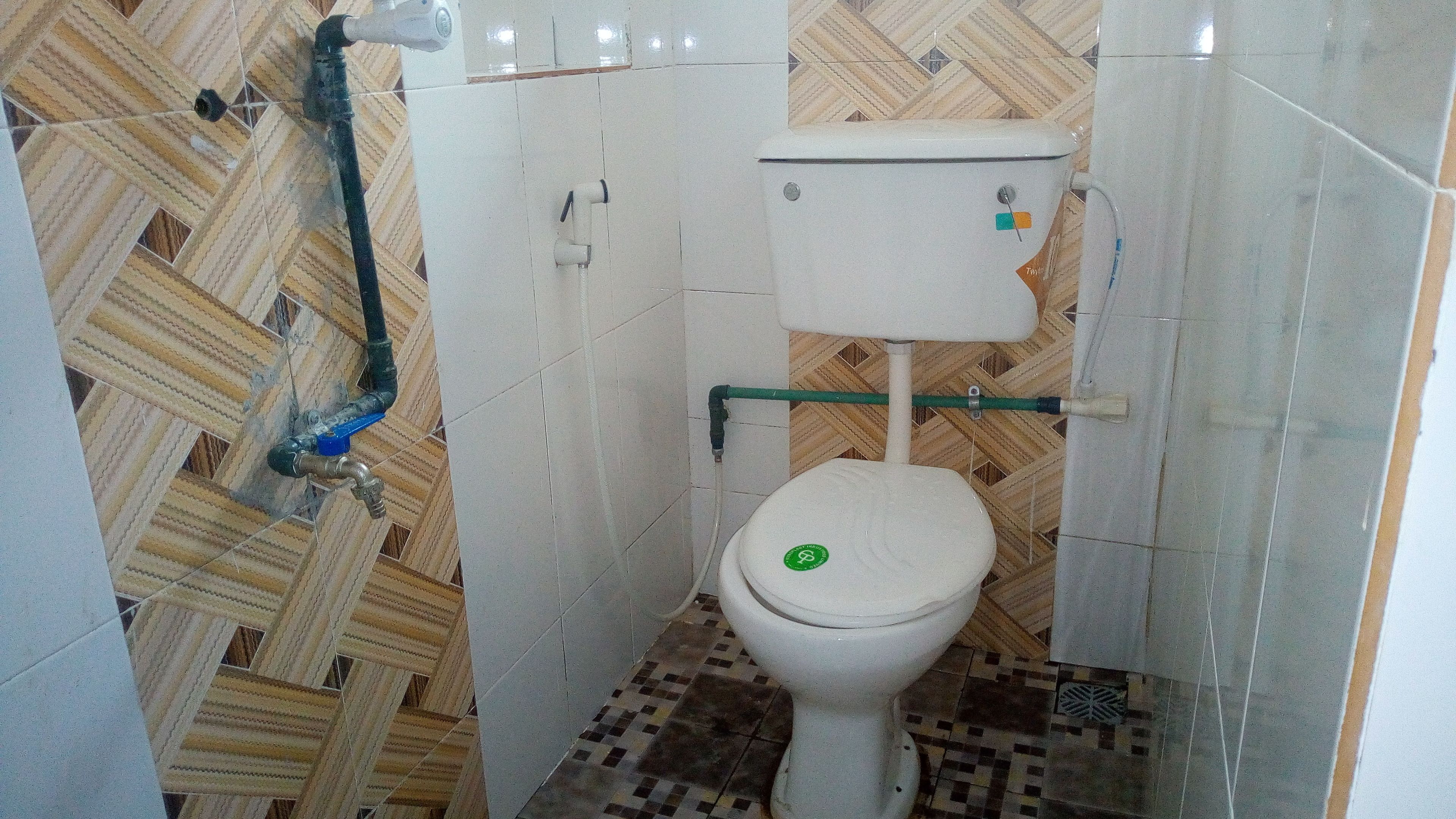 A small bathroom with a toilet, a shower, and a tiled floor.
