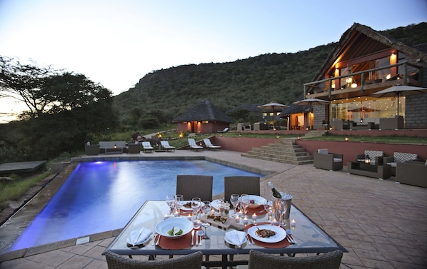 A dining table set for a meal with a pool in the background.