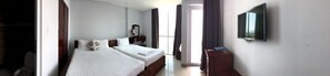 A hotel room with a bed, a bedside table, a TV, and a window with curtains.