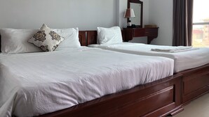 Ein Hotelzimmer mit zwei Betten, einem hölzernen Kopfteil, einem Nachttisch mit Lampe und einem Fenster mit Vorhängen.