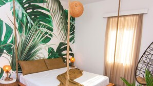 Ein Schlafzimmer mit einem Bett, einem Hängesessel und einer großen Pflanze.
