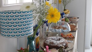 Une table de buffet garnie de divers plats, un vase décoratif rempli de fleurs et des tableaux encadrés accrochés au mur.