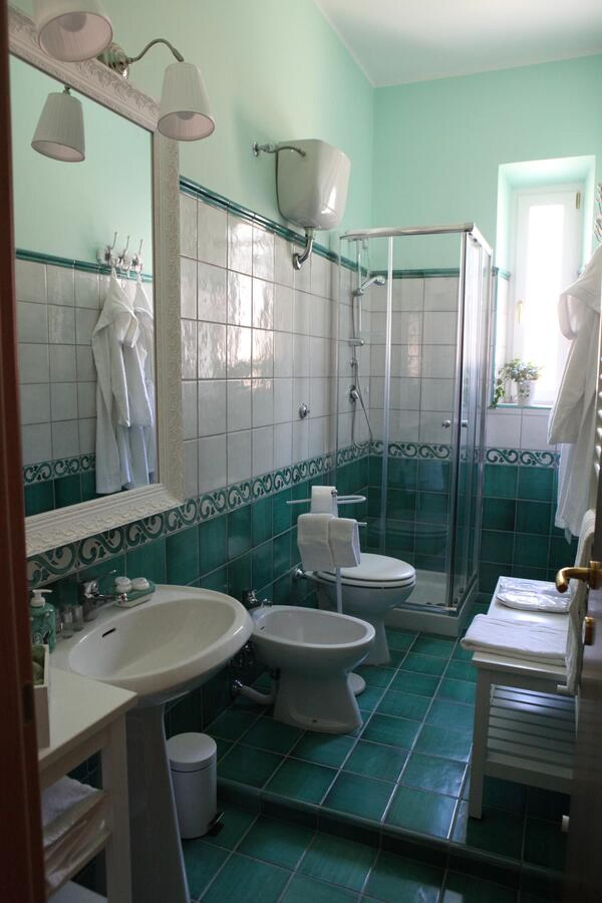 Baño con lavamanos, dos inodoros, ducha y espejo.