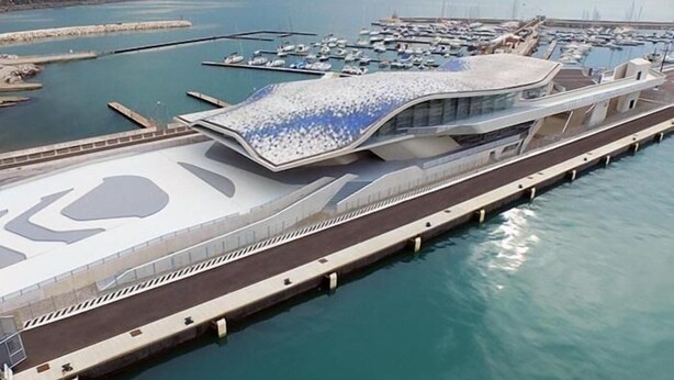 Un port de plaisance moderne doté d’une structure de toit incurvée originale et d’une longue jetée s’avançant dans l’eau.
