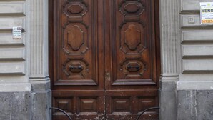 Une porte en bois à deux vantaux, ornée de sculptures complexes, encadrée par un arc surmonté de moulures décoratives.