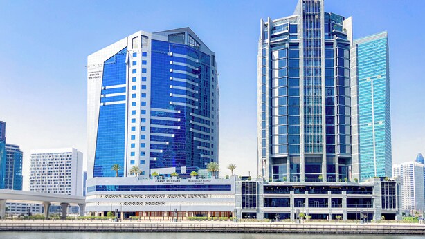 Un edifici modern amb una façana blava destacada, una entrada de vidre gran i vistes al mar.