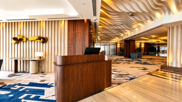 Un hall d’hôtel comprenant un comptoir d’accueil, un espace salon et un tapis à motifs.