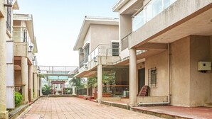 A corridor with a tiled floor, concrete pillars, and balconies with railings. - GuestHouser 5 BHK Bungalow 6931 (Mawal)