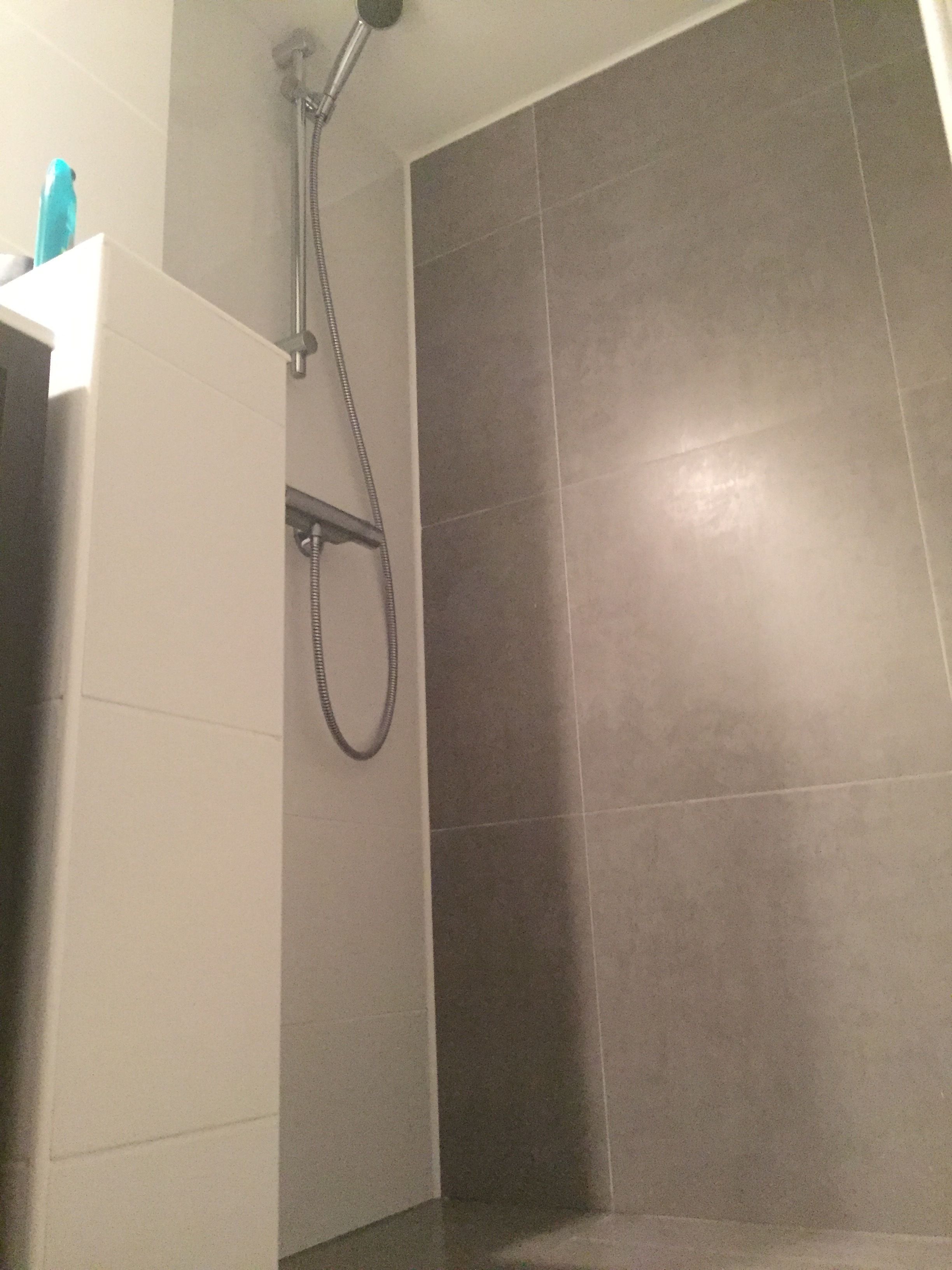 A bathroom with a shower, tiled walls, and a white sink.