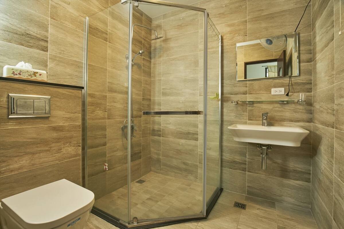 Un bagno moderno con doccia in vetro, lavandino bianco e water.