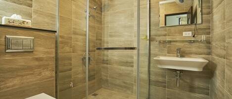 A modern bathroom with a glass-enclosed shower, a white sink, and a toilet.