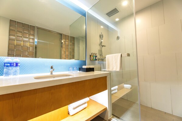 A modern bathroom with a glass shower enclosure, a wooden vanity, and a large mirror. - Holiday Inn Express DaoCheng Yading (Garze)