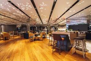 A modern restaurant interior with wooden flooring, multiple seating areas, and a central bar. - Holiday Inn Express DaoCheng Yading (Garze)