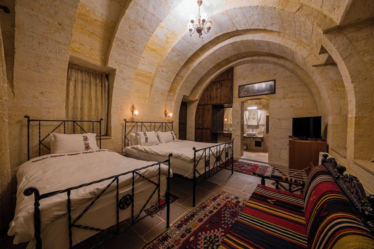 A room with two beds, a television, and a fireplace.