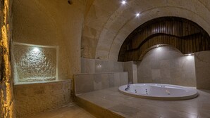 Una stanza spa con parete in pietra, una panca in legno e una vasca da bagno freestanding.