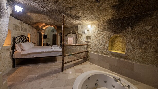 Camera con pareti in pietra, un letto, una sedia di legno e una vasca.