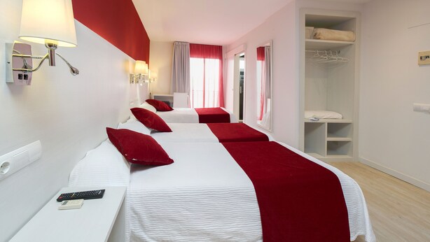 Habitación de hotel con dos camas, un escritorio, un armario y un baño.