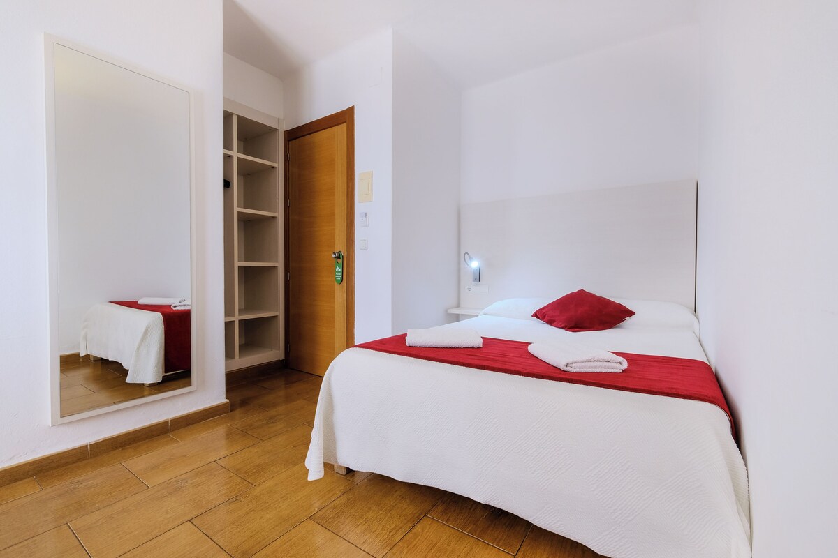 Una habitación de hotel con una cama, un armario y un espejo.