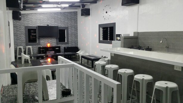 Una cocina moderna con una isla grande, taburetes de bar y un televisor de pantalla plana montado en la pared.