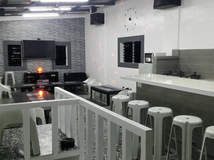 Una cucina moderna con una grande isola, sgabelli da bar e un televisore a schermo piatto montato a parete.