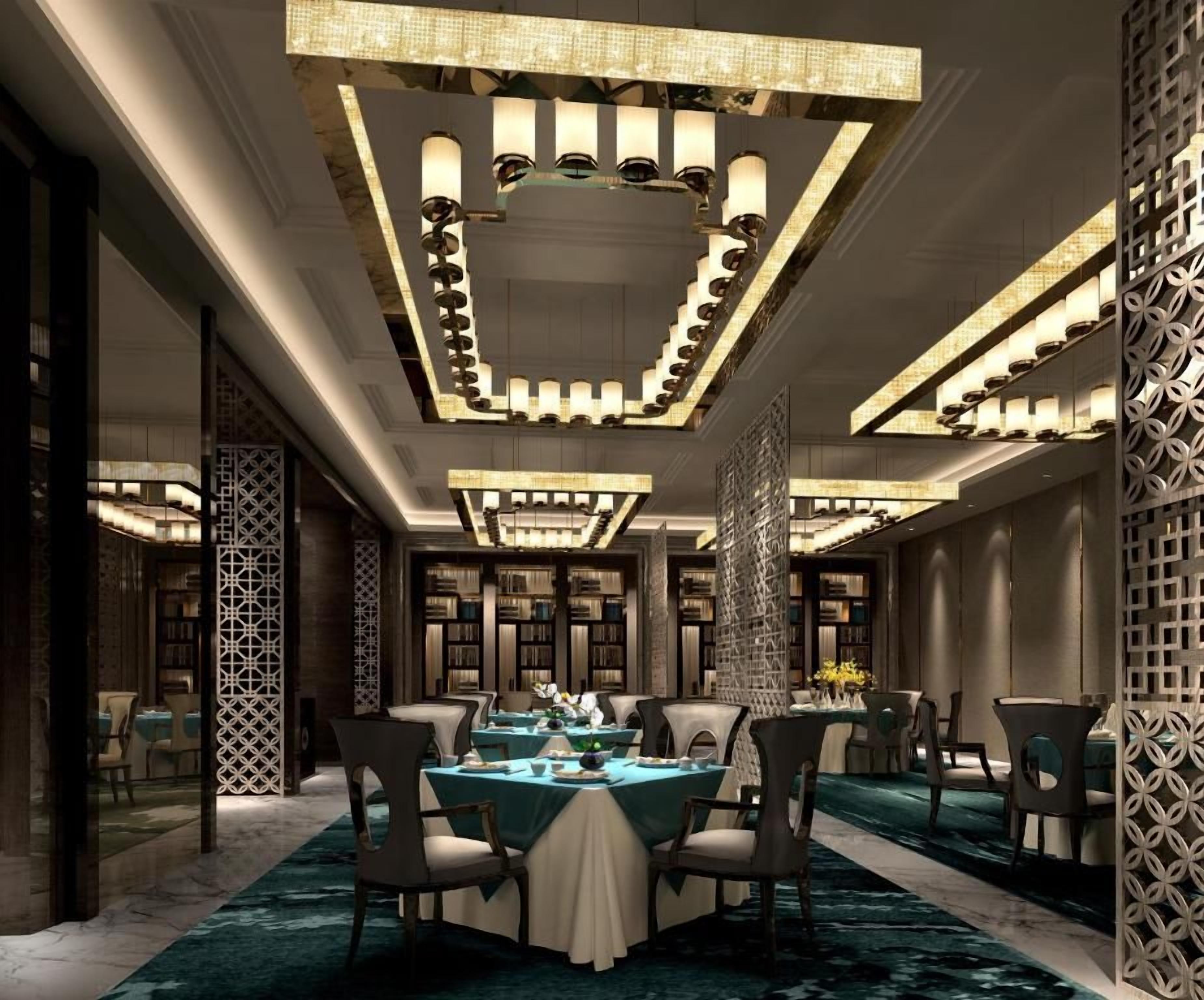 A spacious dining area with multiple tables and chairs, a patterned ceiling, and a decorative wall.
