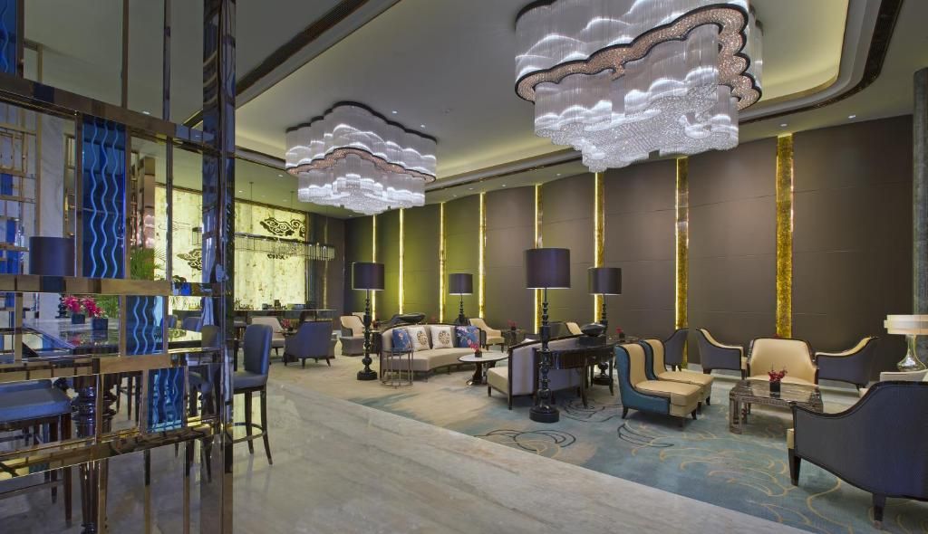 Un moderno vestíbulo de hotel con zona de bar, disposición de asientos e iluminación decorativa.