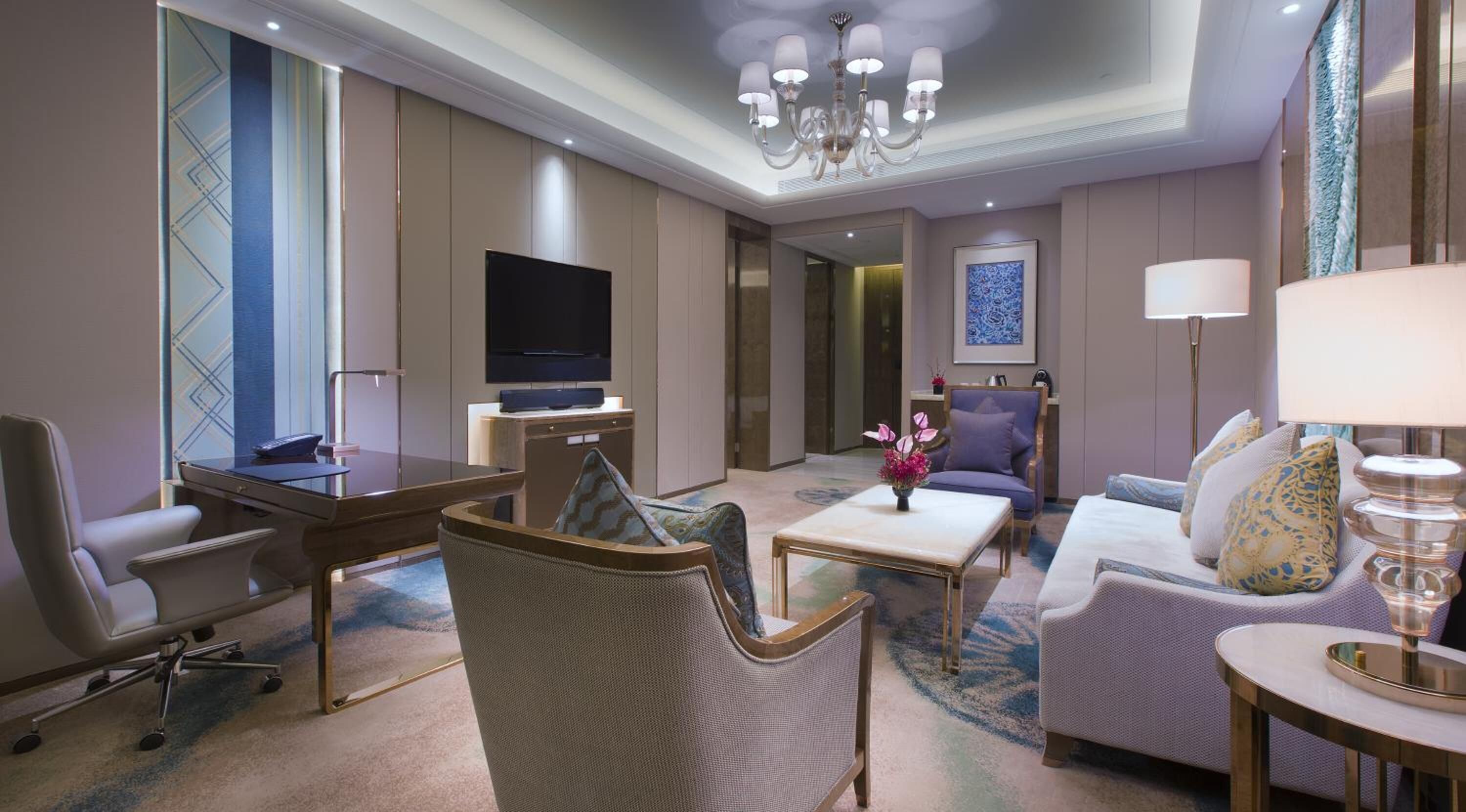 Habitación de hotel con televisión de pantalla plana, escritorio, sofá cómodo, una silla y una mesita de café.