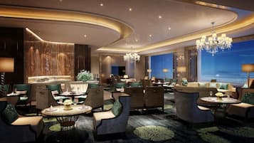A modern hotel lobby with a curved ceiling, chandeliers, and seating areas.