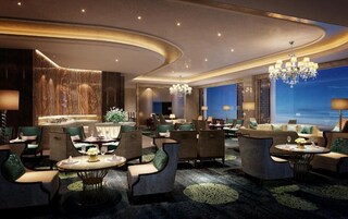 Un moderno vestíbulo de hotel con techo curvo, candelabros y zonas de estar.